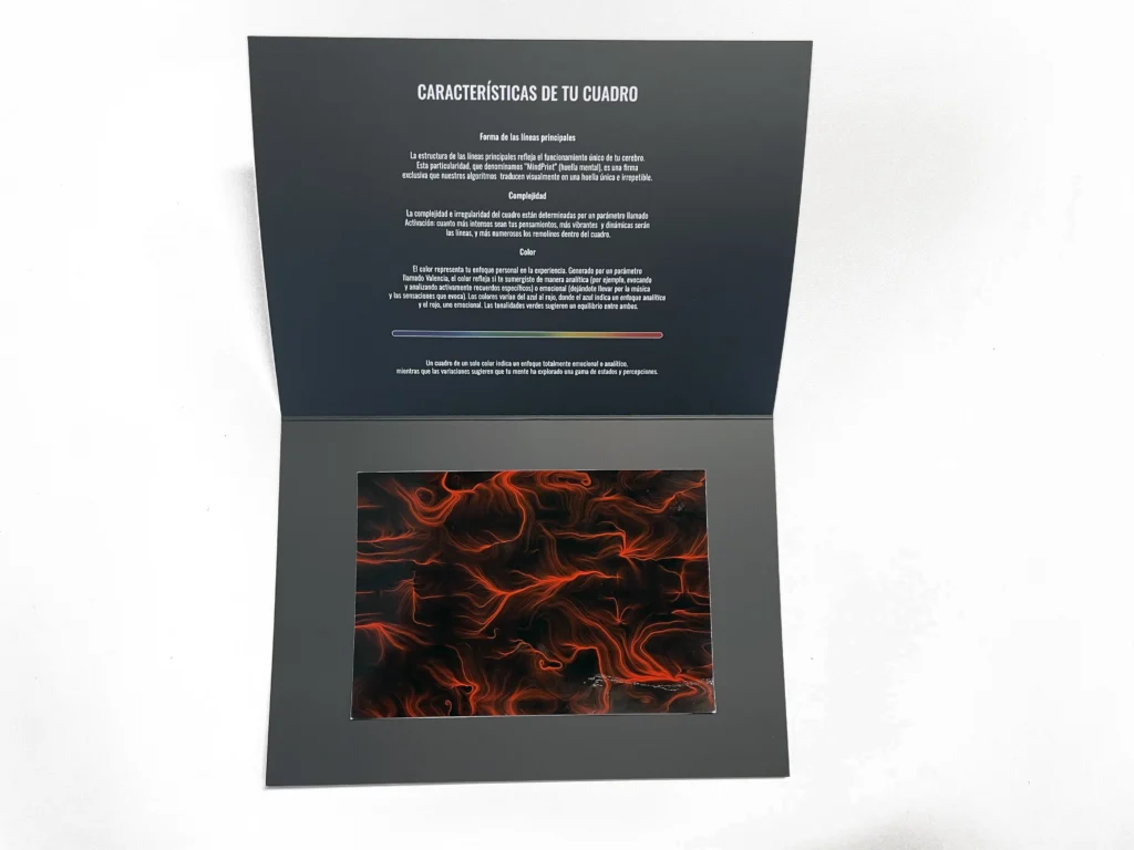 Il pieghevole BrainArt® aperto: nella pagina superiore il testo in spagnolo "Características de tu cuadro" con le sezioni dedicate a forma delle linee, complessità e colore, e in quella inferiore la stampa di un'opera dalle linee e dai vortici arancioni su fondo scuro.