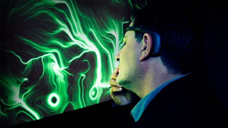 Un uomo di profilo, con un sensore EEG sulla testa e la mano vicino al mento, davanti a uno schermo che mostra un'opera dalle linee e dai vortici verdi su fondo nero.
