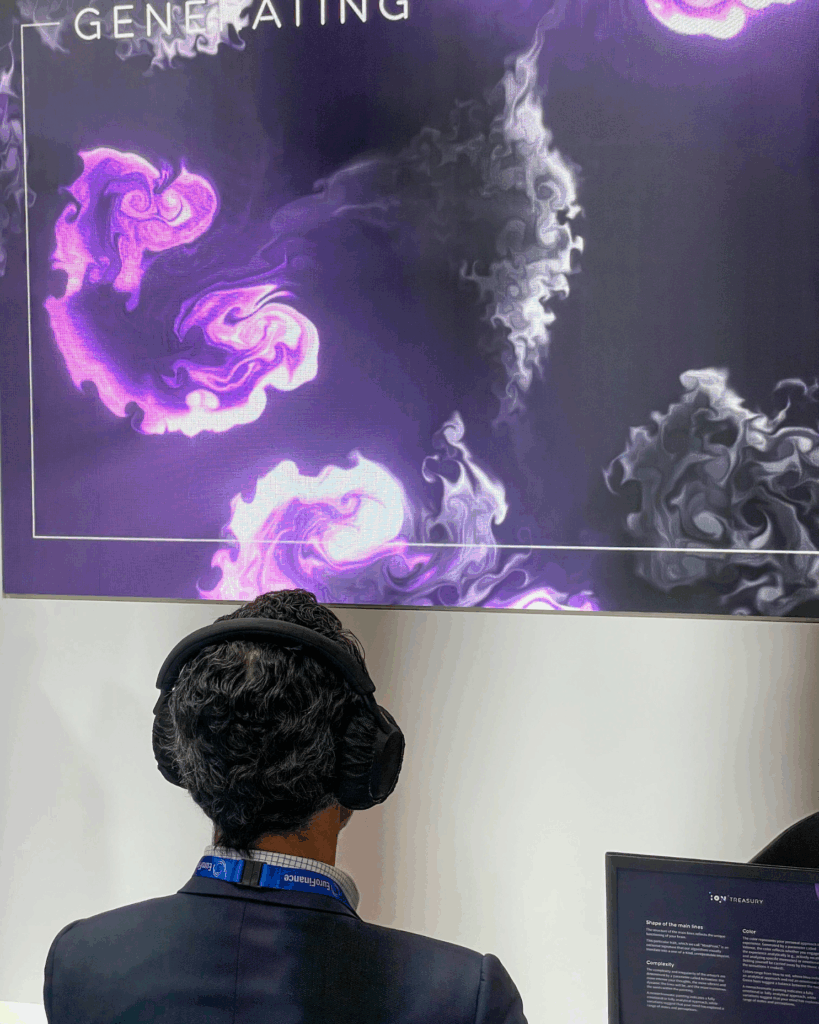Un uomo di spalle, con cuffie e copricapo scuro, osserva un grande schermo con la scritta "GENERATING" che mostra un'opera dai vortici viola e bianchi su fondo scuro; in basso a destra un monitor con il logo ION Treasury.