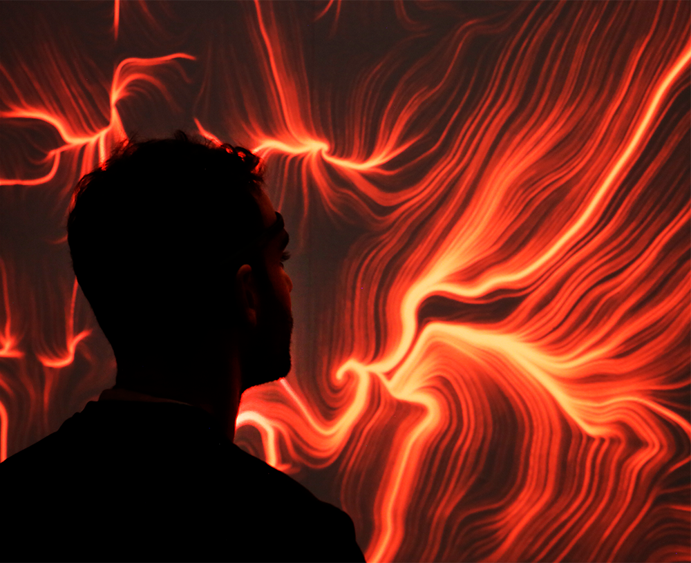Silhouette di un partecipante con sensore EEG davanti a un'opera BrainArt® arancione e rossa generata dalle sue onde cerebrali