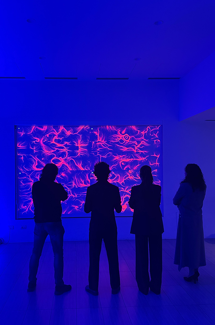 Silhouette di partecipanti davanti a un'opera BrainArt® viola proiettata su grande schermo durante un evento