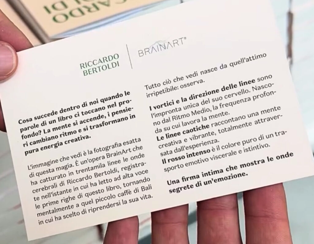 Una mano tiene una card con l'intestazione "Riccardo Bertoldi | BrainArt®" e un testo su due colonne che spiega il significato dell'opera nata dalla sua sessione di lettura.