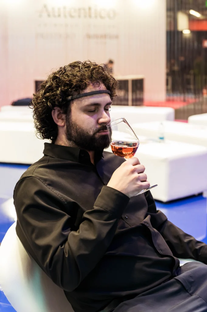 Un ospite con il sensore EEG di BrainArt assapora un calice di vino a occhi chiusi durante la degustazione.