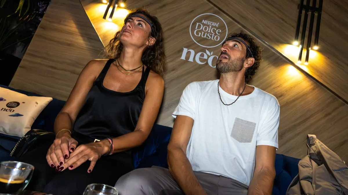 Due ospiti con il sensore EEG in fronte durante l'esperienza BrainArt al lancio di Nescafé Dolce Gusto NEO, con lo sguardo rivolto allo schermo.