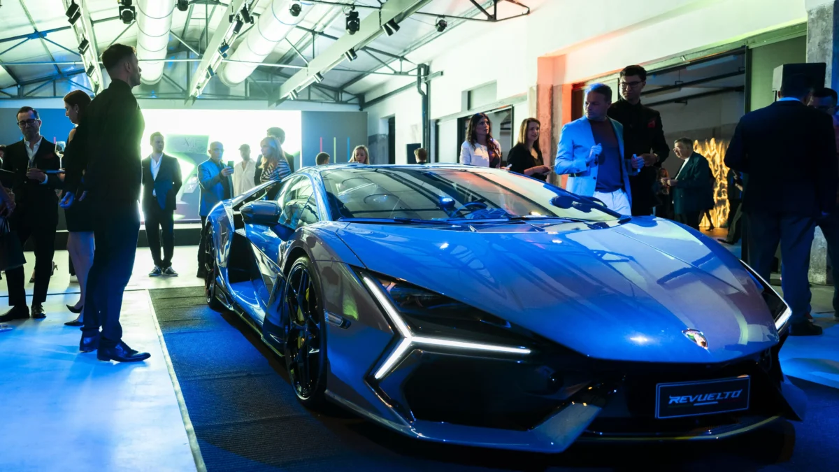 La Lamborghini Revuelto grigia esposta su una pedana illuminata di blu, con alcuni ospiti attorno, durante il lancio della collezione Xerjoff x Automobili Lamborghini.
