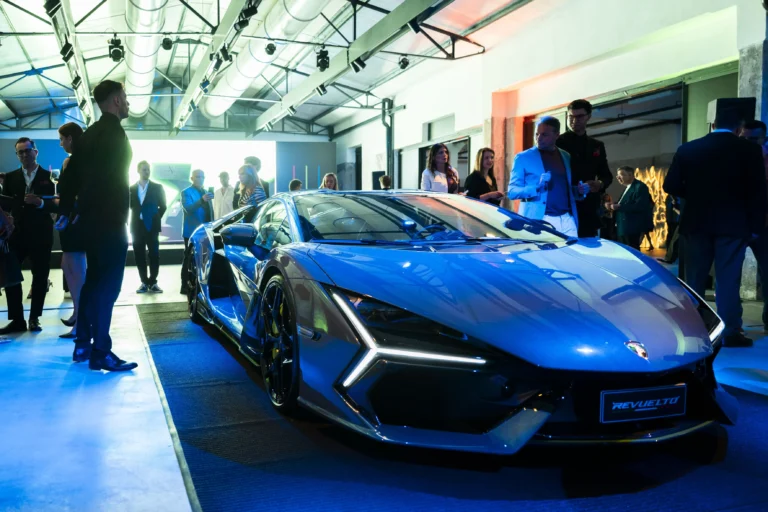 La Lamborghini Revuelto grigia esposta su una pedana illuminata di blu, con alcuni ospiti attorno, durante il lancio della collezione Xerjoff x Automobili Lamborghini.