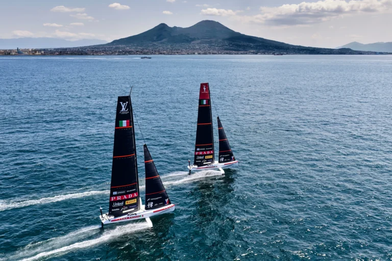 Due imbarcazioni di Luna Rossa in navigazione nel golfo di Napoli con il Vesuvio sullo sfondo, durante le Regate Preliminari dell'America's Cup