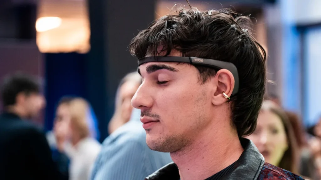 Un ospite a occhi chiusi vive una fragranza tra il pubblico dell'evento, con un sensore EEG sulla fronte e una mouillette tra le dita.