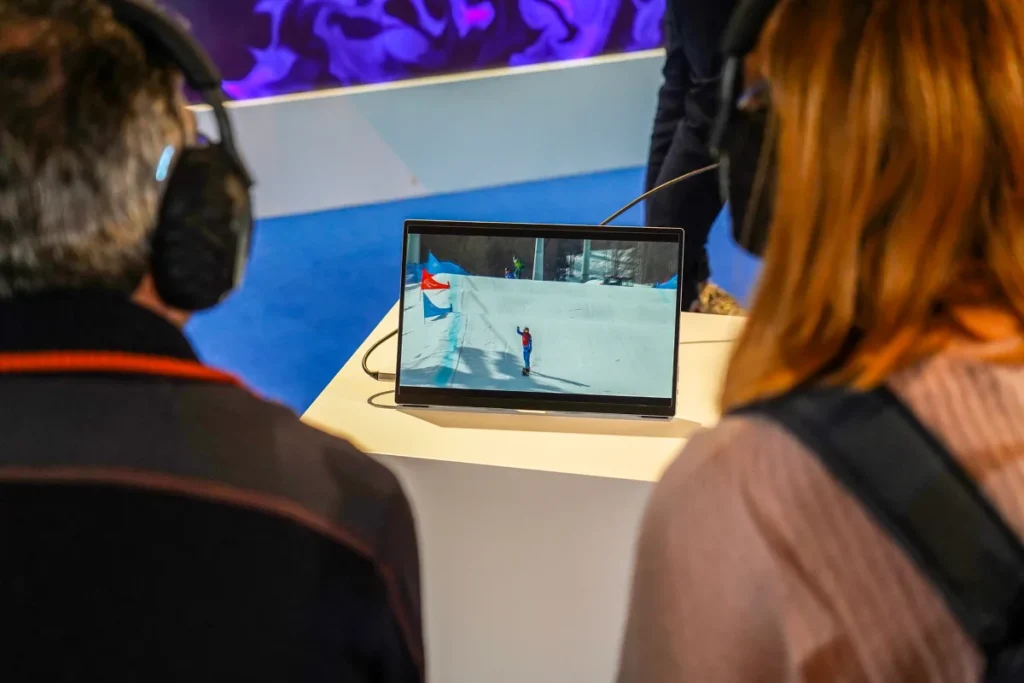 Two participants wearing headphones watch a snowboard athlete on the slope on a monitor during the BrainArt event with Ottobock